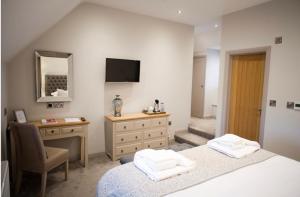 a bedroom with two beds and a desk and a mirror at Rutland Water Courtyard Rooms in Oakham
