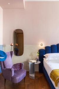 una camera con letto, sedia e specchio di Condominio Monti Boutique Hotel a Roma