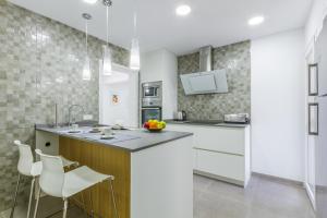 a kitchen with white cabinets and a counter and chairs at Apartment Assimetric - Only 100m to Beach in Alcudia