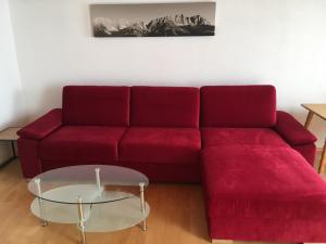 un divano rosso con tavolo in vetro in soggiorno di Pension Schlossberg a Mittersill