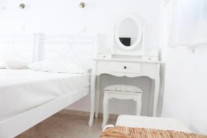 una camera da letto bianca con tavolo da trucco e specchio di Blue Horizon Ios a Ios Chora