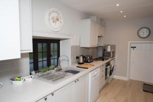 a kitchen with white cabinets and a sink at Rutland Water Courtyard Rooms in Oakham