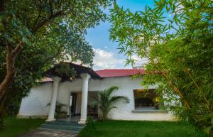 Casa blanca con techo rojo y árboles en Tuli Veer Bagh Resort en Nagpur