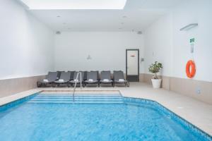 a swimming pool in a room with chairs next to at Plaza Regency Hotels in Sliema