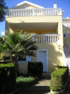 a white house with a balcony and a palm tree at Nikolaos Studios Skala in Skala
