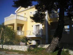 uma casa amarela com uma árvore em frente em Nikolaos Studios Skala em Skála Kefalonias