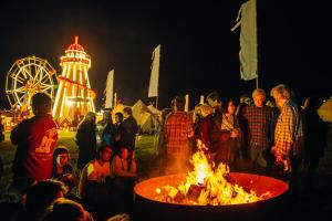 Un gruppo di persone intorno ad un incendio ad una fiera di Festival Yurts Hay-on-Wye a Hay-on-Wye