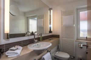 uma casa de banho com um lavatório, um WC e um espelho. em Bavaria Boutique Hotel em Munique