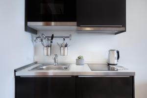 a kitchen with black cabinets and a sink at Plaza Regency Hotels in Sliema