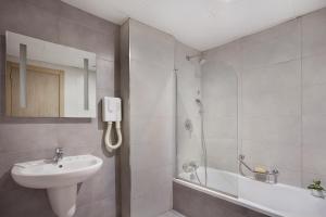 a white bathroom with a sink and a shower at Plaza Regency Hotels in Sliema