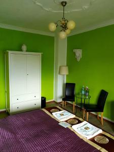 StayInCologne في كولونيا: غرفة خضراء مع كرسيين وخزانة بيضاء