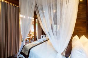 a bedroom with a bed with white curtains at Radiance Sunset Villas Lembongan in Nusa Lembongan +51 photos