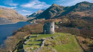 an island with a castle on a hill next to a lake at 11 Llainwen Isaf in Llanberis