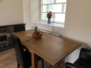 a wooden table with a bowl of fruit and a vase of flowers at 11 Llainwen Isaf in Llanberis +5 photos