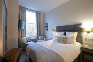 una habitación de hotel con una cama y una silla en 54 Queen's Gate Hotel, en Londres