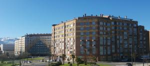 un edificio alto en una ciudad con montañas en el fondo en Apartamento "Los Prados" wifi y parking, en Oviedo