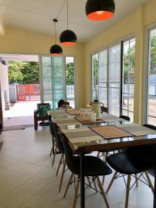 uma sala de jantar com uma longa mesa de madeira e cadeiras em Ban Soi San Sook Homestay em Songkhla