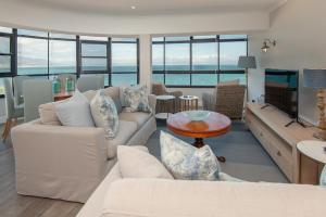 a living room with white furniture and a view of the ocean at The Sun,Whales and Waves seafront apartment in Hermanus