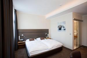 a bedroom with a white bed and a window at Hotel Gräfrather Hof in Solingen