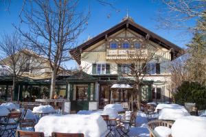 a building in the snow with tables and chairs at Landhaus Café Restaurant & Hotel in Wolfratshausen