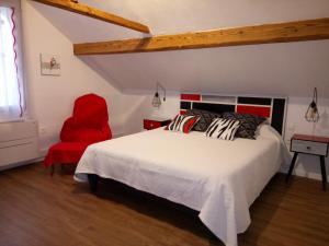 a bedroom with a white bed and a red chair at Chambres d'hôtes Toulaho in Cazères