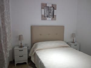 a bedroom with a white bed and two night stands at APARTAMENTO PUERTA SEVILLA in Carmona