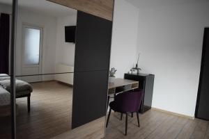 a bedroom with a table and a purple chair at Bruno Apartment in Cluj-Napoca