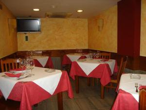ヒホンにあるHotel Doña Mariaの赤白のテーブルクロスが敷かれたテーブル2台付きのレストラン