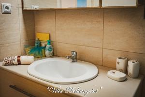 a bathroom counter with a white sink and toiletries at Villa Archangelos in Archángelos +36 photos