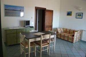 comedor con mesa, sillas y sofá en Appartamento Li Puntiti 2, en Budoni