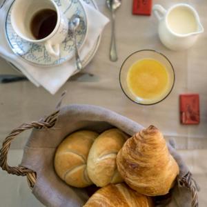 uma cesta de croissants e uma chávena de café numa mesa em B&B Kamerijck em Gingelom