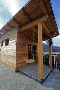 - un bâtiment en bois avec une terrasse couverte et une balançoire dans l'établissement One room, à Sauze dʼOulx