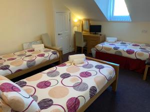 Habitación con 3 camas y escritorio con ordenador. en Austins Guest House en Cardiff