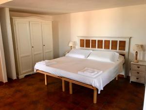 a bedroom with a large bed with white sheets and pillows at Hotel Su Meriagu in Capitana