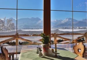 een tafel in een kamer met uitzicht op de met sneeuw bedekte bergen bij Seehotel Hartung & Ferienappartements in Füssen
