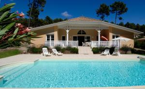 a house with a swimming pool in front of it at Lagrange Vacances - Atlantic Green in Lacanau-Océan