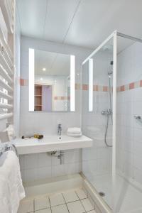 La salle de bains blanche est pourvue d'un lavabo et d'une douche. dans l'établissement Hotel Club Le Plein Sud Vacances Bleues, à Hyères