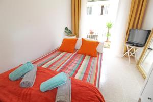 a bedroom with a bed with orange pillows and a tv at Casco histórico in Alicante