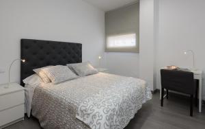 a bedroom with a bed with a black headboard and a desk at Apartamentos Lanceata in Revolta