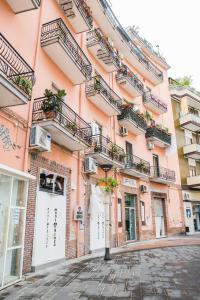 a pink building with balconies on a cobblestone street at Vittoria Guest House Battipaglia in Battipaglia