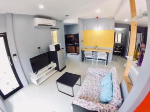 ein Wohnzimmer mit einem Sofa, einem Tisch und einem TV in der Unterkunft The Endless Bangtao Residence LOFT 7 in Strand Bang Tao
