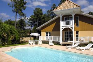 a house with a swimming pool in front of a house at Lagrange Vacances - Eden Club in Lacanau-Océan
