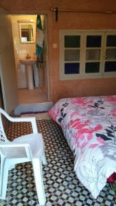 een slaapkamer met een bed, een stoel en een wastafel bij gîte les jardins in Goulmima