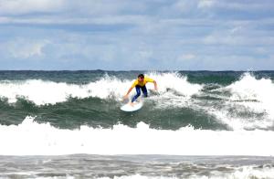 a man riding a wave on a surfboard in the ocean at Lagrange Vacances - Eden Club in Lacanau-Océan