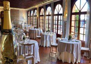 een kamer met tafels en stoelen met witte tafels en ramen bij Relaisfranciacorta in Corte Franca