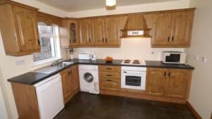 a kitchen with wooden cabinets and a white stove top oven at Three bedroom holiday home in Port