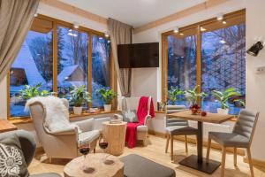 a living room with chairs and tables and windows at Hotel Foluszowy Potok in Zakopane