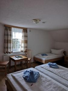 um quarto com 2 camas, uma mesa e uma janela em Gasthof Widenschek em Thalheim