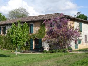 stary kamienny dom z purpurowym drzewem w obiekcie La Pénardière w mieście Saint-Étienne-de-Tulmont