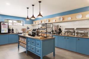 a kitchen with blue cabinets and a counter with food at Country Inn & Suites by Radisson, Belleville, ON in Belleville